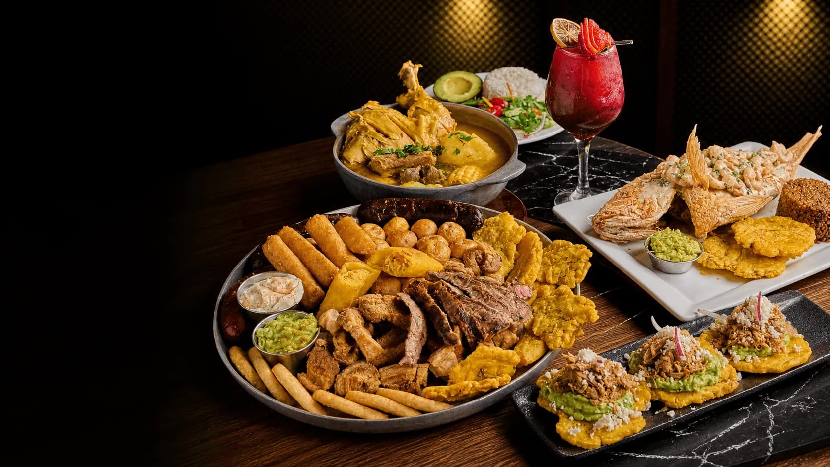 Colombian food spread at La Ruana, a Colombian restaurant in Peachtree Corners, with a mixed platter, fried fish, patacones and a cocktail